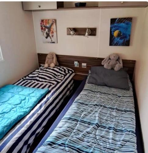 two beds in a room with two stuffed animals at Mobil home in Biscarrosse