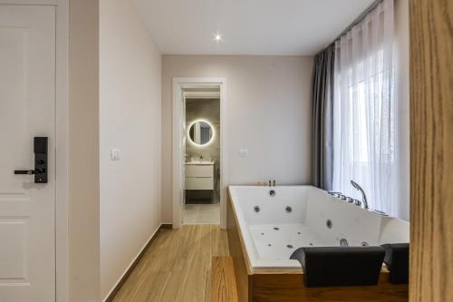 a bathroom with a large white tub and a window at Sea La Vie Suites in Golem