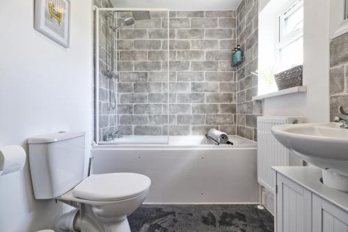 a bathroom with a toilet and a tub and a sink at Colchester 4BR Home, Sleeps 8, Fast WiFi, Perfect for Contractors in Hythe