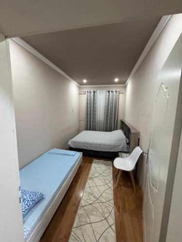 une petite chambre avec deux lits et une chaise dans l'établissement Arditi's Guesthouse, à Shkodër
