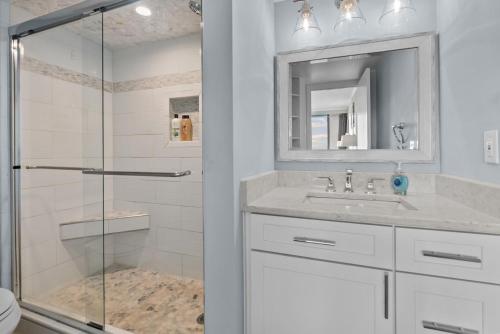a bathroom with a shower and a sink and a mirror at Beachfront Condo/ Pool/ Surfing/ Fishing / EW 1202 in Virginia Beach