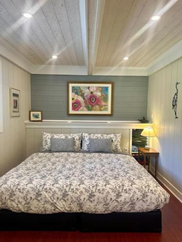 a bedroom with a bed and a painting on the wall at Captain Cottage in Bowen Island