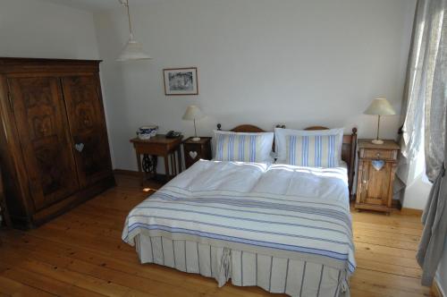 a bedroom with a bed with white sheets and wooden floors at Auberge de la Gare in Grandvaux