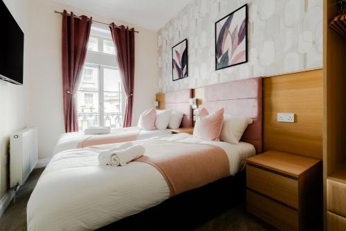 two beds in a hotel room with red curtains at Mina Hotel by PLI in London