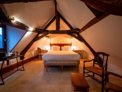 a bedroom in an attic with a bed and a bench at Les Remparts Hôtels et Demeures Historiques in Beaune