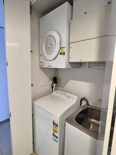 a small kitchen with a sink and a refrigerator at Modern 1BR Views in Belconnen in Belconnen