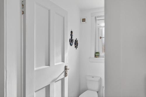 a white bathroom with a toilet and a door at Troon Golf by the Sea in Troon