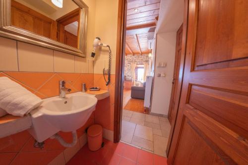a bathroom with a sink and a mirror and a door at xenonas ton xromaton - Guest house of colors in Lafkos
