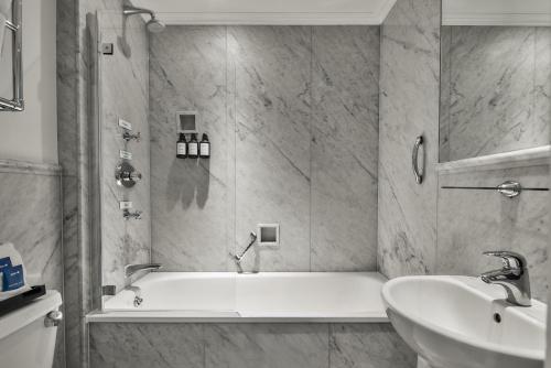 ein Badezimmer mit einer weißen Badewanne und einem Waschbecken in der Unterkunft Radisson Blu Hotel, London South Kensington in London