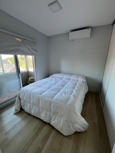 a bedroom with a white bed in a room with a window at Depto Berazategui Centro in Berazategui