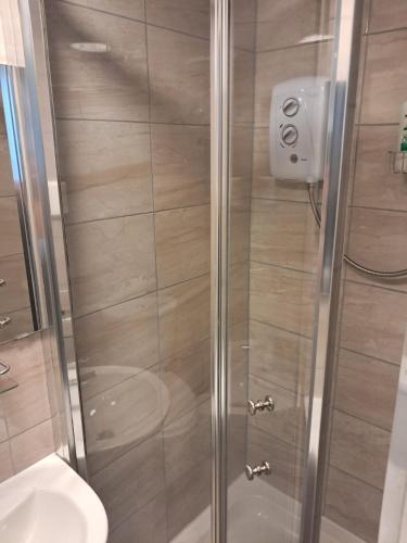 a shower with a glass door next to a toilet at Saint Annes Guest House - 22 Berkeley in Dublin