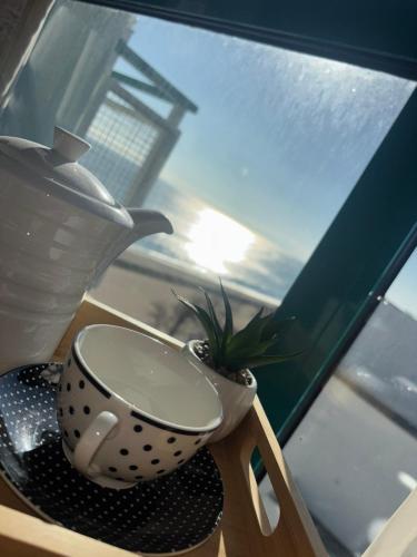 a cup and a plant on a table next to a window at Berlin Golden Beach Studio in Varna City
