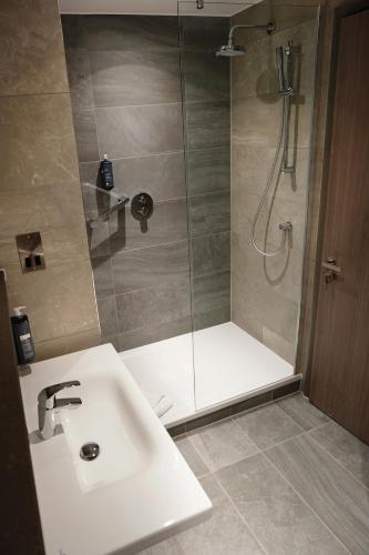 a bathroom with a shower and a white sink at Maldron Hotel Glasgow City in Glasgow