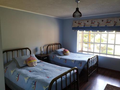 a bedroom with two beds and a window at Casa de Campo, tranquilidad natural in Curicó