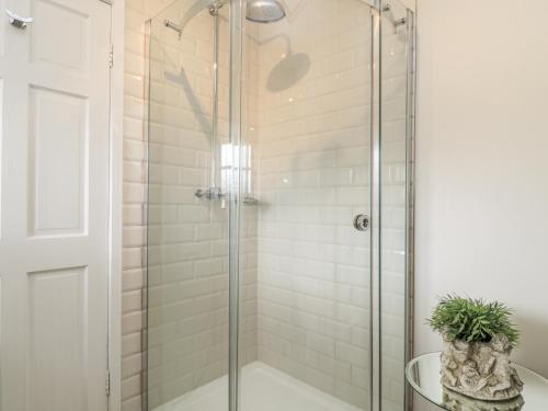 a shower stall with a glass door in a bathroom at Ostlers in Burford