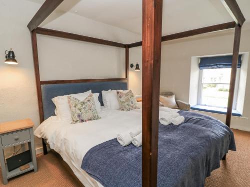 a bedroom with a four poster bed with towels at Ostlers in Burford