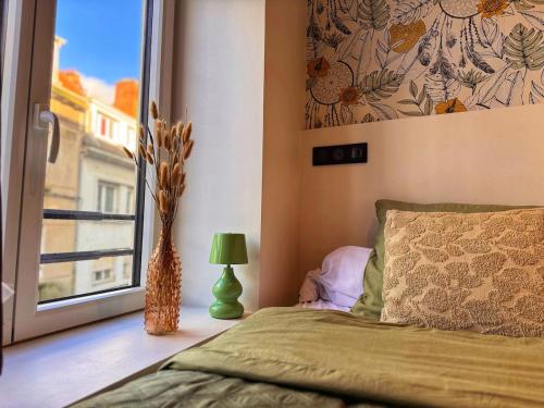a bedroom with a bed and a window and a vase at Le Cocon de Rose & Achille in Boulogne-sur-Mer