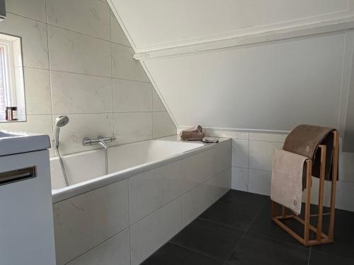 a white bathroom with a tub and a sink at B&B De Holevoet in Scherpenzeel