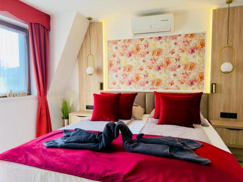 a bedroom with a bed with red pillows at Villa Peonia-Szauna & Relax in Keszthely