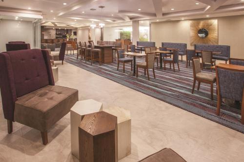 a restaurant with tables and chairs in a lobby at La Quinta by Wyndham Aguascalientes in Aguascalientes
