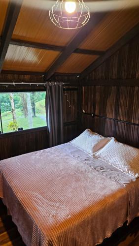 a bedroom with a bed in a room with a window at Chalé lindo e confortável! in Massaranduba