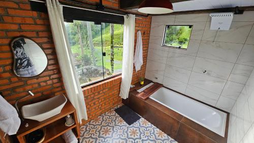 a bathroom with a tub and a sink and a window at Chalé lindo e confortável! in Massaranduba