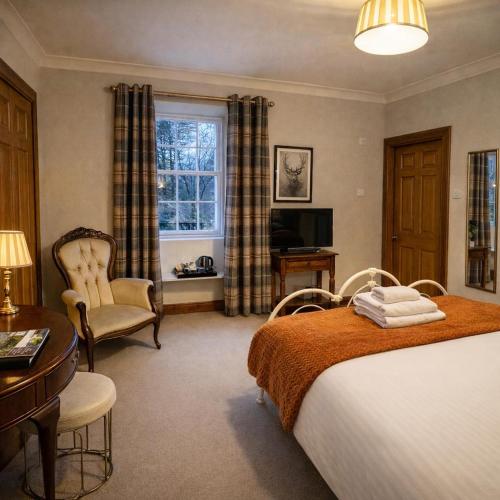 a bedroom with a bed and a desk and a window at Killean Farmhouse B&B in Inveraray