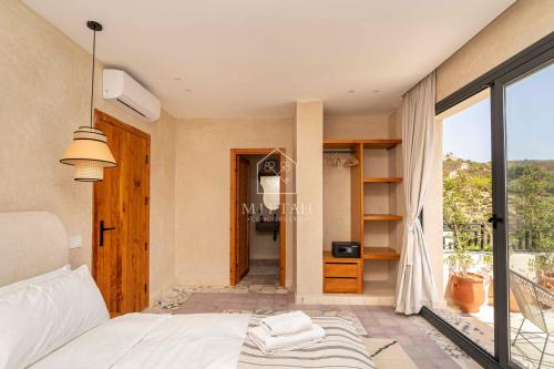 a bedroom with a bed and a large window at Chambre avec vue panoramique in Noûnouech