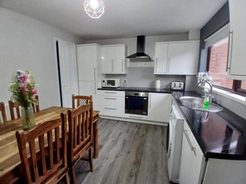 a kitchen with white cabinets and a table and chairs at MASSIVE 4 Bed home walking distance to the City lights, perfect for business trips in Belfast