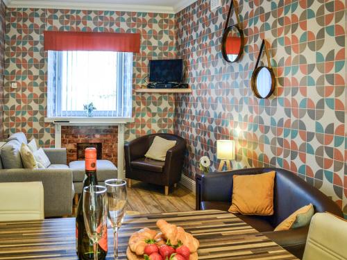 a living room with a table with a bottle of wine at Park View Cottage in Stranraer