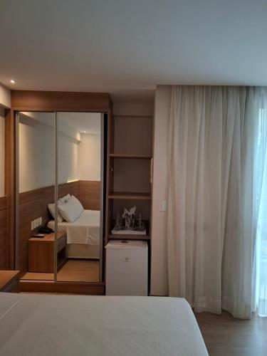 a bedroom with a bed and a mirror at Vista Azul Apart Hotel - Vista Pedra Azul in Pedra Azul