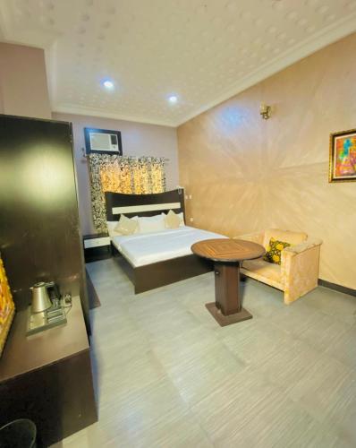 a bedroom with a bed and a table and a couch at Garden Atlantis Hotel in Enugu