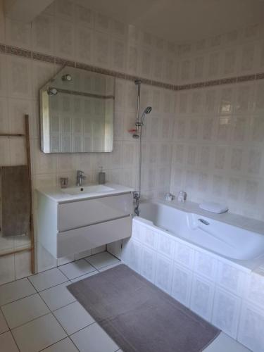 a white bathroom with a tub and a sink at Chrysalide in Baillif