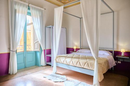 a bedroom with a canopy bed and a window at Palazzo Mercanzia in Lecce