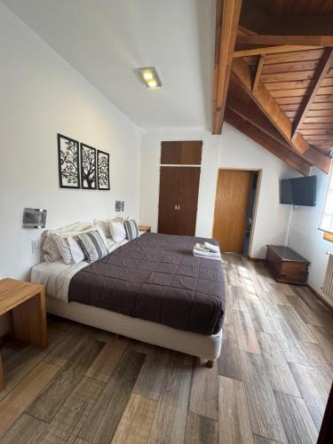 a bedroom with a large bed and a wooden floor at Hostería Cumbres Blancas in Esquel