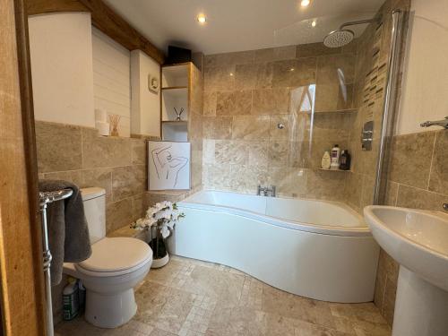 a bathroom with a tub and a toilet and a sink at The barn Alexandra mews in Heathfield