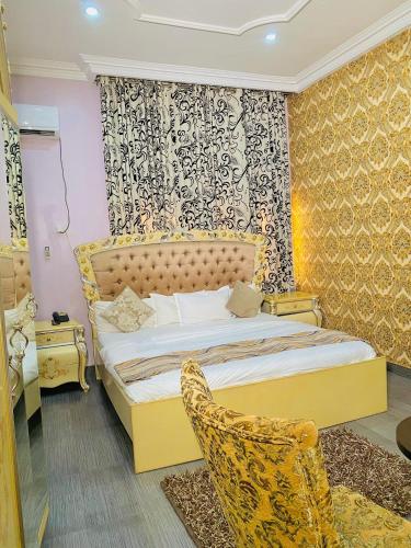 a bedroom with a yellow bed and a chair at Garden Atlantis Hotel in Enugu