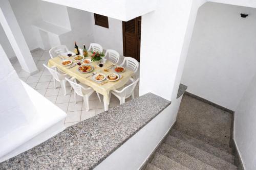 a table with white chairs and food on it at Casa Saracino 3 - Semplicità Mediterranea in Marina di Pescoluse