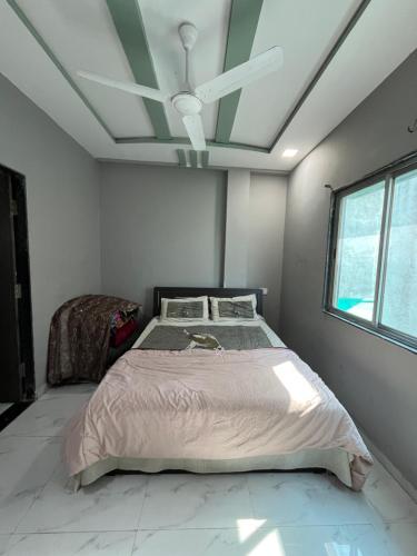 a bedroom with a bed and a ceiling fan at Green Heaven Stay in Surat