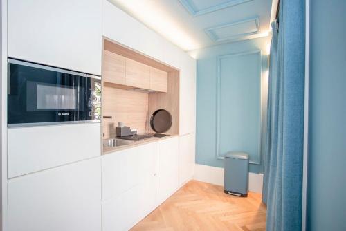 a kitchen with white cabinets and a television in a room at Liiiving in Porto - Ribeira Design Apartment in Porto