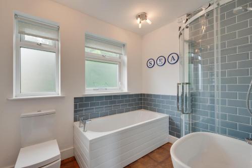 a bathroom with a tub and a shower with blue tiles at 5 Bed in Woolacombe oc-alba12 in Woolacombe