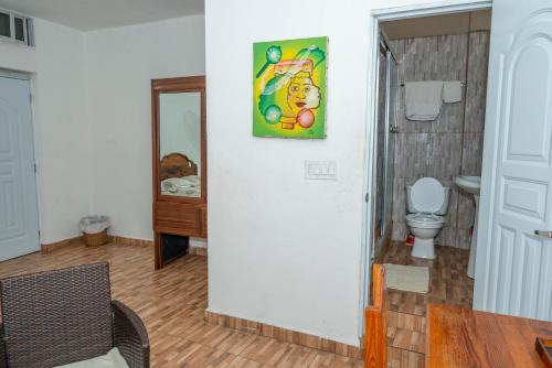 a bathroom with a toilet and a painting on the wall at Preloune Residences SA in Cap-Haïtien