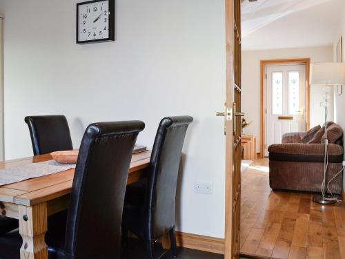 a dining room table with black chairs and a clock on the wall at The Costins in Allonby