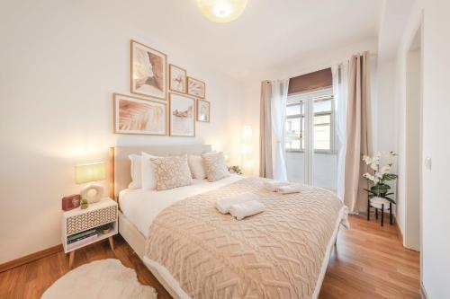 a white bedroom with a large bed and a window at GuestReady - Charming Oeiras apartment in Oeiras