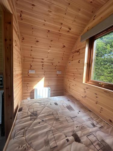 a bed in a log cabin with a window at Ronam Glamping 2 Berth Pod in Anderby