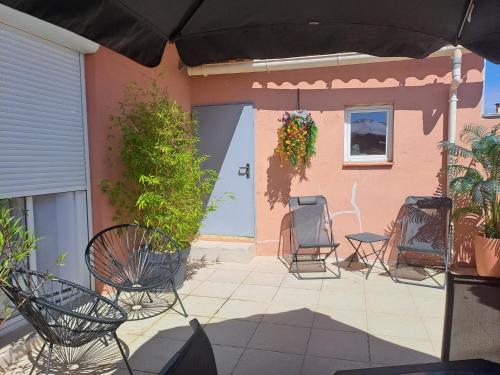 un patio con sedie e un ombrellone davanti a una casa di Chic et douillet a Perpignano
