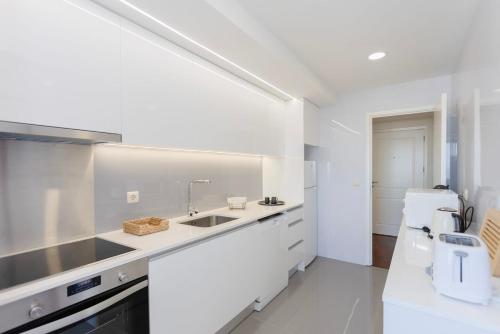 a white kitchen with a sink and a counter at Liiiving in Matosinhos - Seaside Balcony Apartment in Porto
