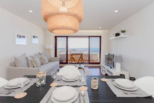 a living room with a couch and a table with plates at Liiiving in Matosinhos - Seaside Balcony Apartment in Porto