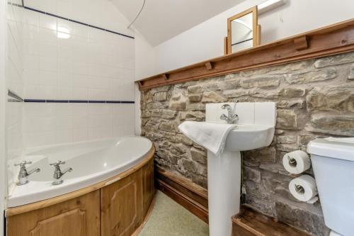 a bathroom with a stone wall and a tub and a sink at 3 Bed in Knighton oc-b29329 in Felindre