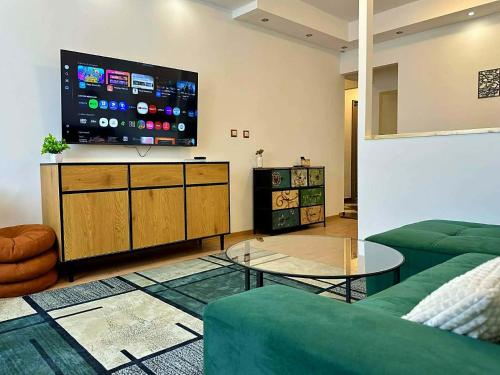 a living room with a green couch and a flat screen tv at VestaLak in Tata